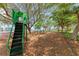 Outdoor playground featuring green slides and swings amidst a leafy, shaded area near waterfront homes under a bright blue sky at 4616 Leeta Ln, Sarasota, FL 34234