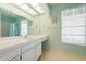 Well-lit bathroom with a vanity, mirror, and walk-in shower with turquoise accents at 465 Laurencin Dr, Nokomis, FL 34275