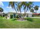 Single story home with 2 car garage featuring lush landscaping, mature palms, and a circular garden at 465 Laurencin Dr, Nokomis, FL 34275