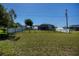 Large, grassy backyard enclosed by a combination of white and black metal fencing for privacy at 552 Bellaire Dr, Venice, FL 34293