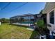 Backyard view featuring a screened in pool, mature palm trees, and a privacy fence at 552 Bellaire Dr, Venice, FL 34293