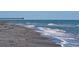 Expansive beach view with gentle waves lapping on the sandy shore under a clear sky at 552 Bellaire Dr, Venice, FL 34293