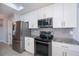 Well-lit kitchen featuring stainless steel appliances, granite countertops, tile flooring and bright white cabinetry at 552 Bellaire Dr, Venice, FL 34293