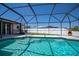 Backyard pool is surrounded by a screened enclosure, landscaping, and white fencing at 552 Bellaire Dr, Venice, FL 34293