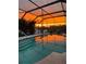 Beautiful pool with a screened enclosure reflecting the vibrant sunset sky at 552 Bellaire Dr, Venice, FL 34293