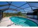 Backyard pool is surrounded by a screened enclosure, landscaping, and white fencing at 552 Bellaire Dr, Venice, FL 34293