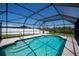 Backyard pool is surrounded by a screened enclosure, landscaping, and white fencing at 552 Bellaire Dr, Venice, FL 34293