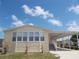 Charming, light yellow single-Gathering home with attached carport, lush green grass, and bright blue sky at 554 Aspen Ave, Venice, FL 34285