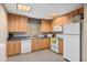 Cozy kitchen featuring wooden cabinets and white appliances at 5739 Sabal Trace Dr # 102, North Port, FL 34287