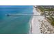 Wide aerial view showcasing a pier, sandy beach, and turquoise ocean waters at 5853 Semolino St, Nokomis, FL 34275