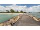 Picturesque view of a sandy beach, turquoise water, and a rock breakwater barrier under a sunny sky at 5853 Semolino St, Nokomis, FL 34275