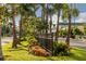 Charming street view with mature palm trees, lush landscaping, a black fence, and a building in the distance at 5853 Semolino St, Nokomis, FL 34275