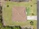 Birds-eye view of a well-maintained home with a brown roof, surrounded by green grass and mature landscaping at 6199 Stamp St, Port Charlotte, FL 33981