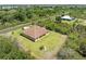 Aerial view of a cozy single-story home on a spacious lot with green lawns and surrounding natural landscape at 6199 Stamp St, Port Charlotte, FL 33981
