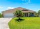 Charming single-story home boasts a lush lawn, a mature palm tree, and a two-car garage at 6199 Stamp St, Port Charlotte, FL 33981
