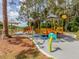 Beautiful view of a new colorful playground with a sunshade surrounded by lush green grass and mature trees at 6231 Jordan St, North Port, FL 34287