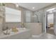 Luxurious bathroom with a soaking tub, glass shower, and neutral tile at 629 Ibiza Loop, Venice, FL 34292