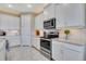 Well-lit kitchen features stainless steel appliances, light countertops, white cabinetry, and tile flooring at 629 Ibiza Loop, Venice, FL 34292