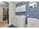 Laundry room with blue brick-patterned accent wall, sink, white cabinets, and washer/dryer at 629 Ibiza Loop, Venice, FL 34292