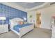 Charming main bedroom features a blue accent wall, white furniture, and plush bedding at 629 Ibiza Loop, Venice, FL 34292