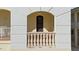 Close-up of a balcony with stone balusters and an arched entryway to the front door at 63 Palm Dr, Placida, FL 33946