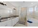 Elegant bathroom featuring double sinks, granite countertop, soaking tub, and a glass-enclosed shower at 63 Palm Dr, Placida, FL 33946