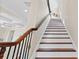 Staircase with dark wood railings, white risers, and dark wood treads with detailed iron work at 63 Palm Dr, Placida, FL 33946