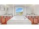 Bright bathroom featuring a large soaking tub, separate vanities, and a window with scenic water views at 632 Tanana Fall Dr, Ruskin, FL 33570