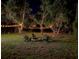 Night view of the backyard featuring a fire pit with chairs and outdoor lights at 6497 Honeycomb Cir, North Port, FL 34291