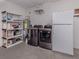 Laundry room features a washing machine, dryer, refrigerator, water heater, and plastic shelving at 6497 Honeycomb Cir, North Port, FL 34291