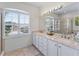 Well-lit bathroom featuring double sinks, a large mirror, and a window with plantation shutters at 678 Clear Creek Dr, Osprey, FL 34229