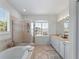 Bright bathroom featuring a soaking tub, glass shower, and double vanity with shuttered window at 678 Clear Creek Dr, Osprey, FL 34229