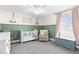 Charming Bedroom with green walls, white crib, gray rocking chair, and a large window for natural light at 755 Mohawk Rd, Venice, FL 34293