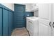Modern laundry room with blue walls, updated machines, and clean white cabinets at 755 Mohawk Rd, Venice, FL 34293