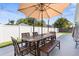 Backyard patio with a wooden table set, shade umbrella, and well-manicured lawn at 755 Mohawk Rd, Venice, FL 34293