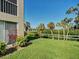 Backyard view featuring a spacious lawn and waterfront scenery with palm trees at 821 Waterside Dr # 106, Venice, FL 34285