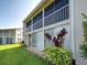 Back exterior showcasing a two-story condo with sliding glass doors, a balcony, and lush green lawn at 821 Waterside Dr # 106, Venice, FL 34285