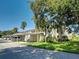 Condominium building featuring covered parking, mature landscaping, and a well-maintained lawn at 821 Waterside Dr # 106, Venice, FL 34285