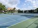 View of the community tennis court with a building and trees in the background at 821 Waterside Dr # 106, Venice, FL 34285