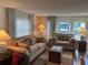 Comfortable living room featuring matching sofas, a decorative rug, and natural light streaming through large windows at 902 Jolanda Cir, Venice, FL 34285