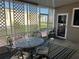 A screen porch shows a table and seating, all well lit from natural sunlight, and a view of the outdoors at 902 Jolanda Cir, Venice, FL 34285