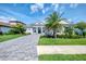 Beautifully landscaped front yard with palm trees and a paver driveway, enhancing this modern home's curb appeal at 9048 Luna Ln, Sarasota, FL 34241