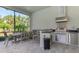 Well-equipped outdoor kitchen with stainless steel appliances, ample counter space, and a large dining table at 9048 Luna Ln, Sarasota, FL 34241