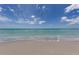 Serene view of the beach with calm turquoise water and soft sand under a partly cloudy sky at 976 Euclid Rd, Venice, FL 34293
