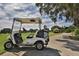 A white golf cart is parked on a paved path beside a lush green fairway with trees at 976 Euclid Rd, Venice, FL 34293