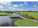 Scenic golf course with a winding wooden bridge over a tranquil lake on a bright sunny day at 976 Euclid Rd, Venice, FL 34293