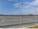 Outdoor tennis court enclosed by a chain-link fence under a sunny, partly cloudy sky at 976 Euclid Rd, Venice, FL 34293
