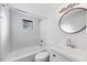Bright bathroom with a white tub, tile surround, and a white vanity featuring modern fixtures at 1032 Elaine St, Venice, FL 34285