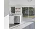 Modern kitchen featuring stainless steel dishwasher, open shelving, and a large sliding glass door to the yard at 1032 Elaine St, Venice, FL 34285
