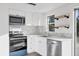 Well-lit kitchen with stainless steel appliances, white cabinets, marble backsplash, and open shelving at 1032 Elaine St, Venice, FL 34285